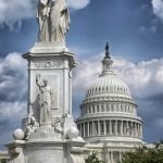 US Capitol building with Peace Monument statue under dramatic clouds.